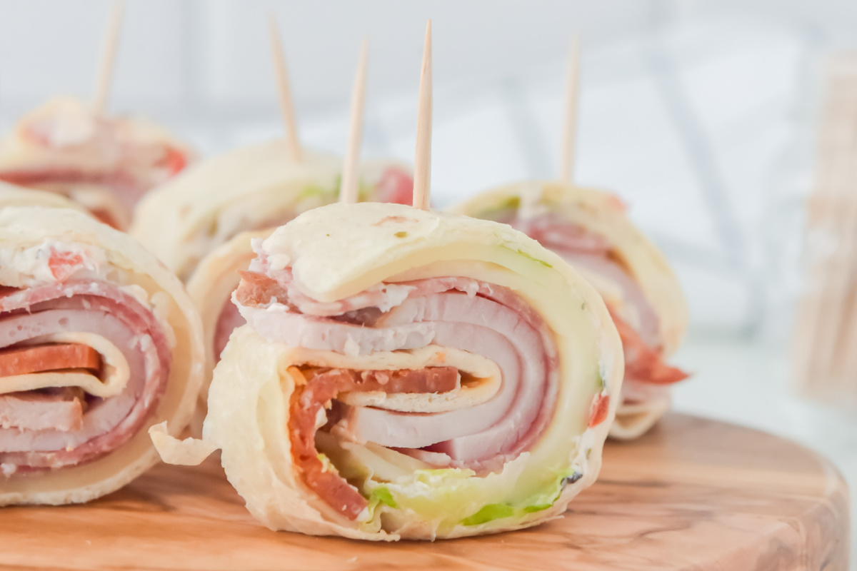 Italian pinwheels with toothpicks on a wooden cutting board.