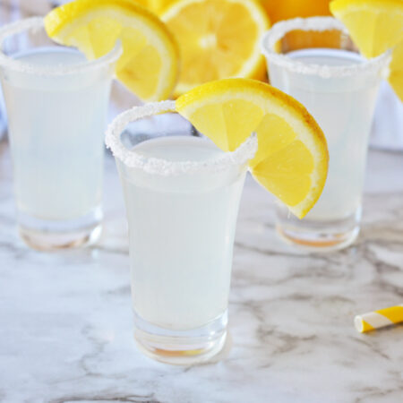 Three glasses of lemonade with a slice of lemon, perfect for a refreshing lemon drop shot recipe.