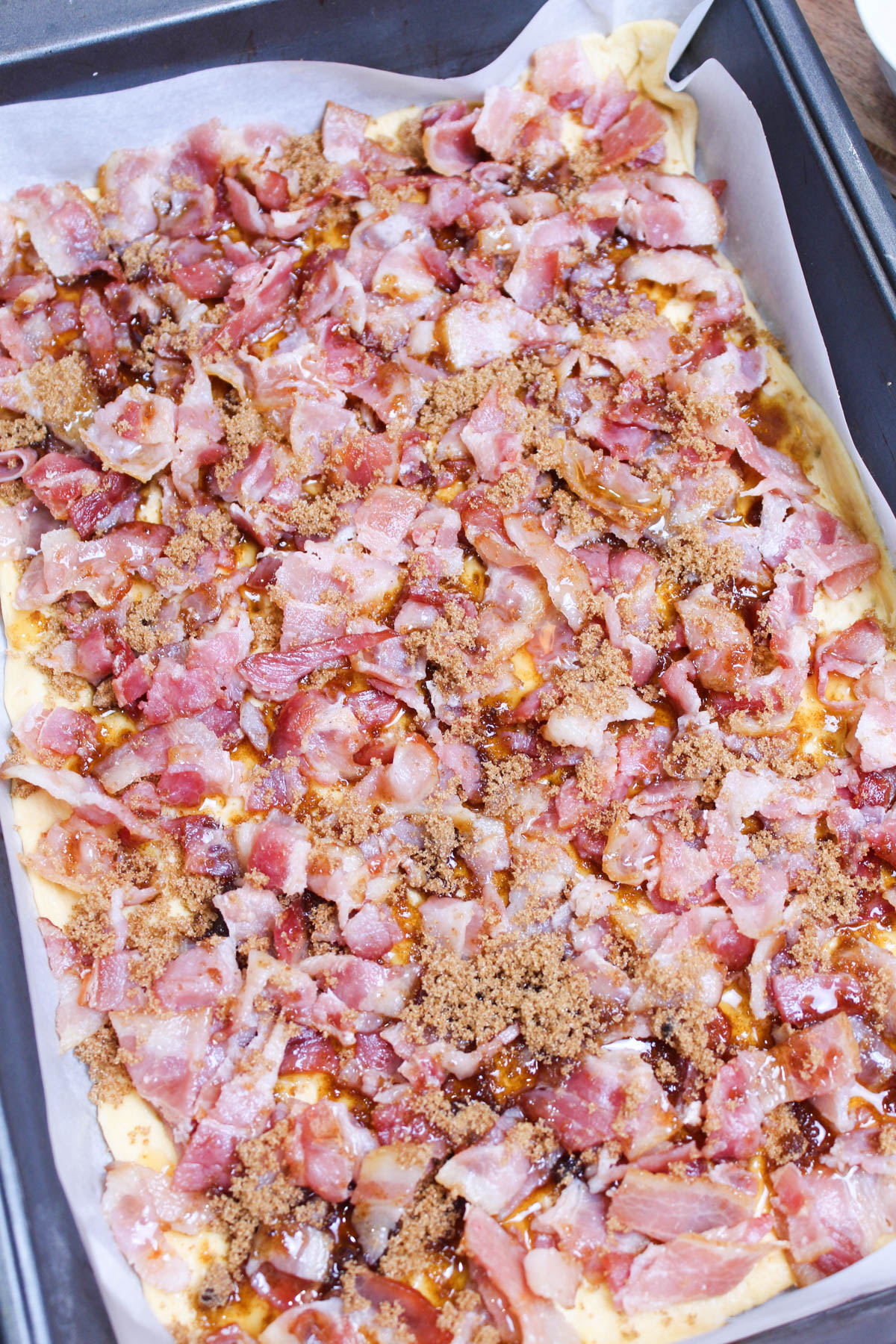 A pizza with bacon and cheese in a pan on a table.
