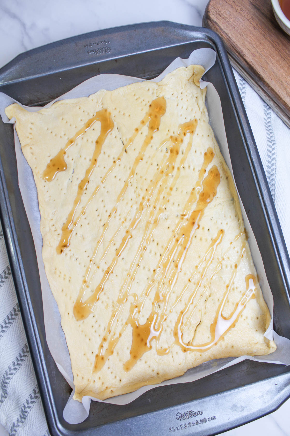 A baking sheet with crescent roll dough with syrup on it.