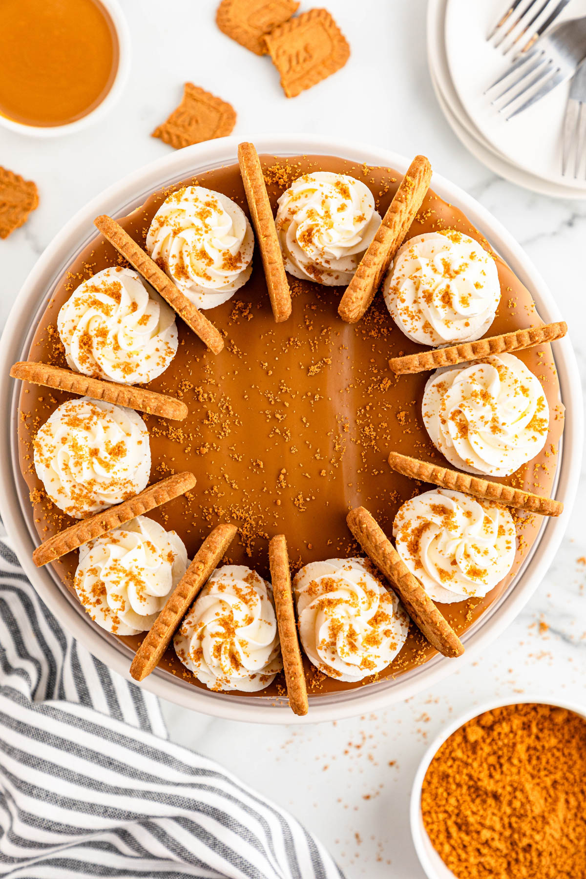 A Biscoff cheesecake with whipped cream and graham crackers on a plate.