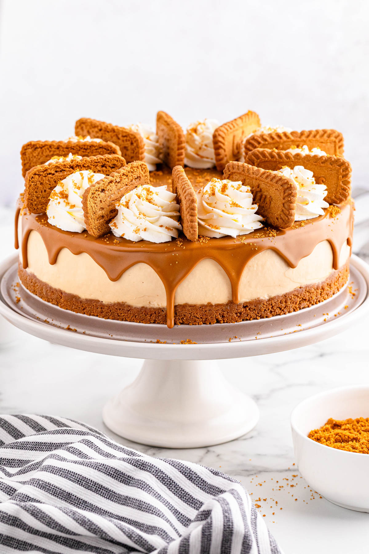 A cheesecake on a cake stand with whipped cream on top.