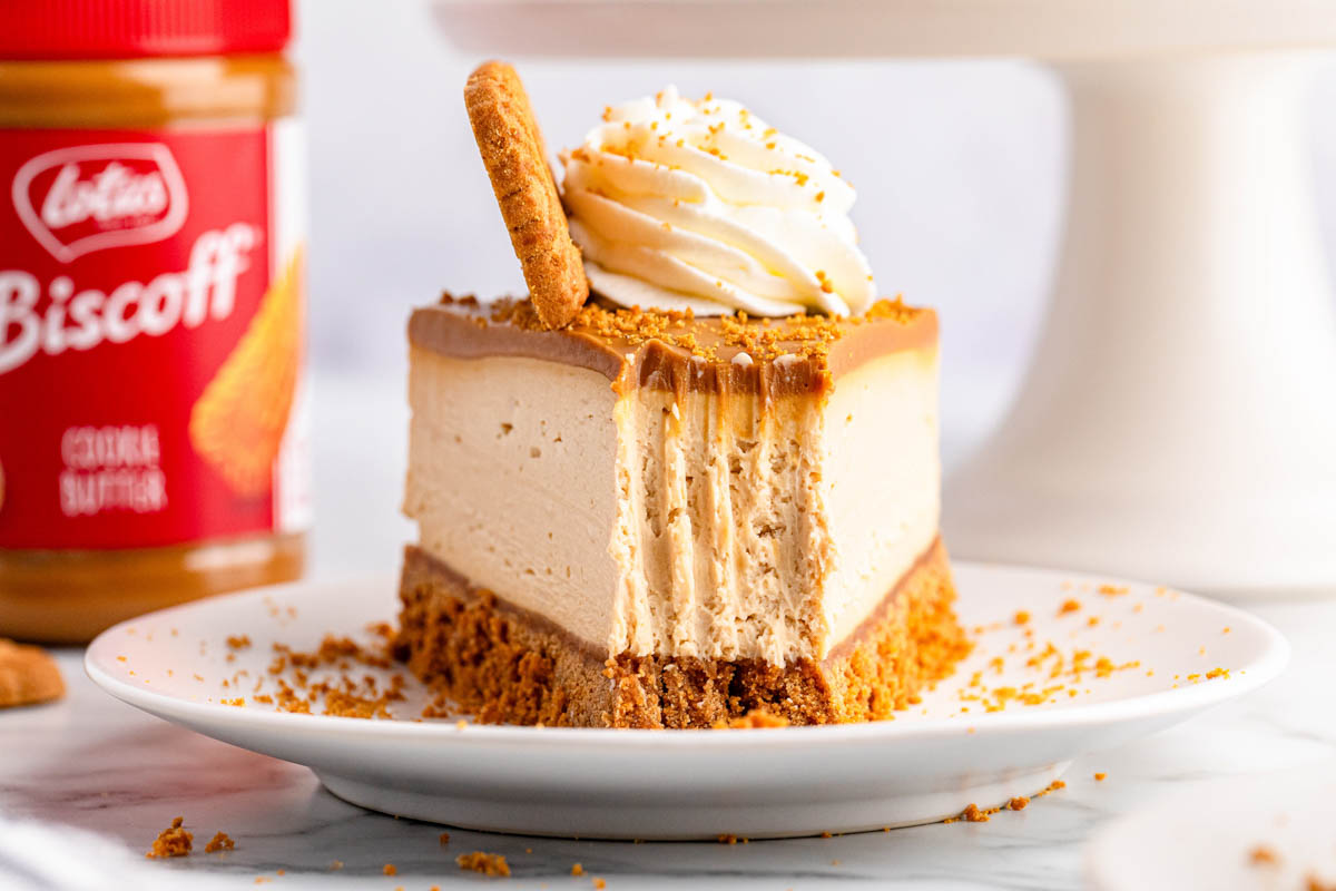 A slice of Biscoff cheesecake on a plate with a jar of Biscoff spread