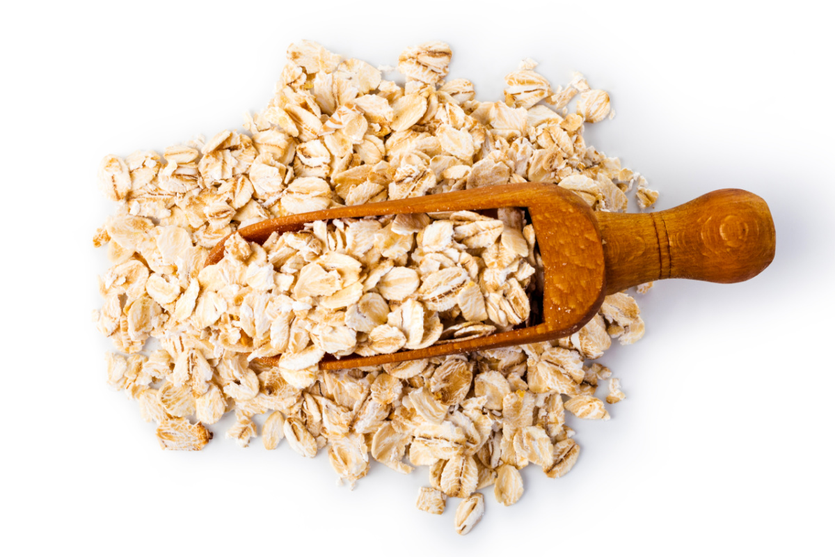 Oats in a wooden scoop on a white background.