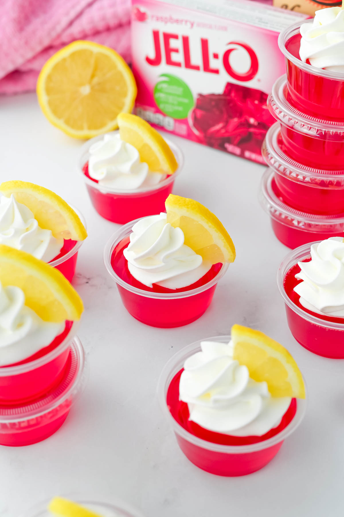Raspberry Lemon jello shots with whipped cream and lemon slices.