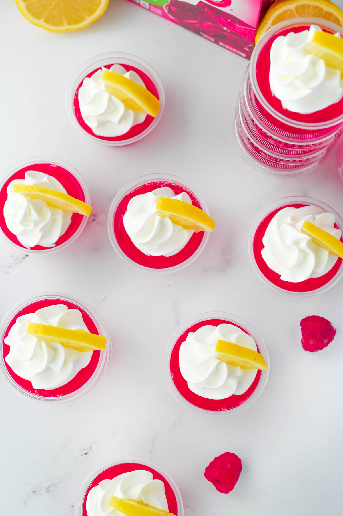 Raspberry lemonade jello shots with whipped cream and lemons.