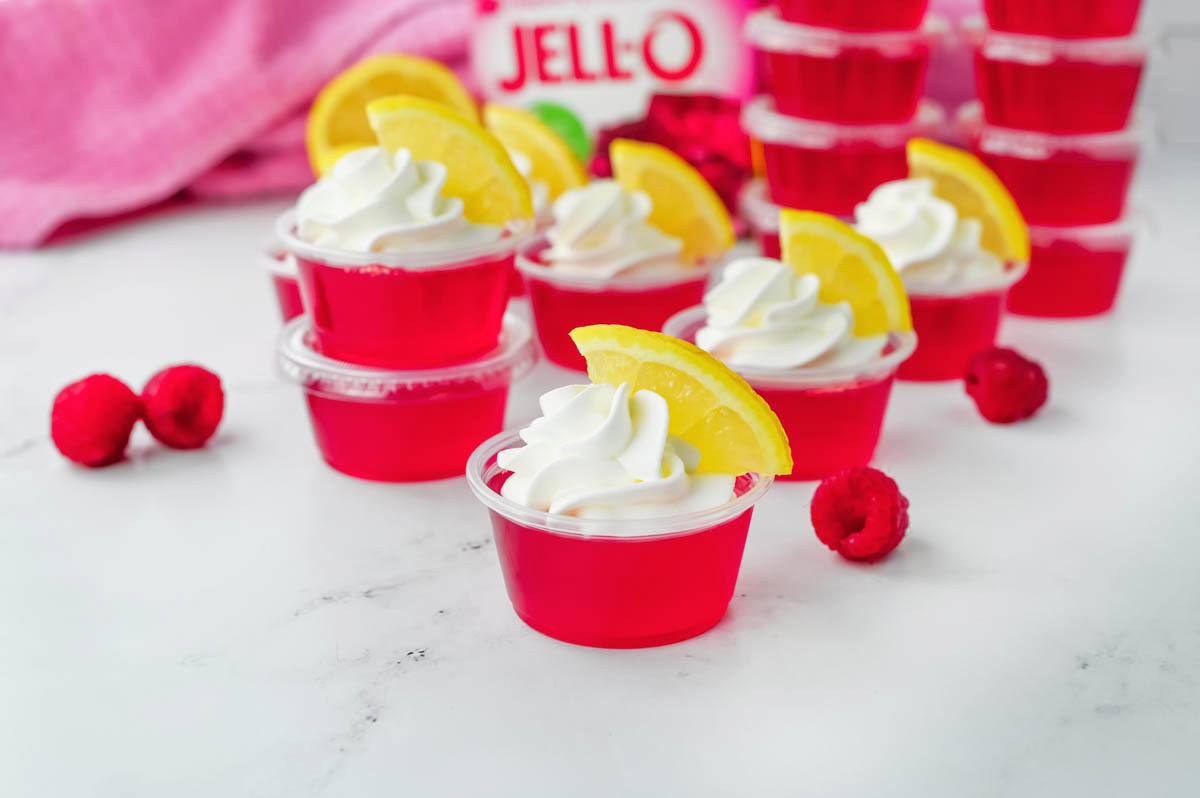 Raspberry lemon jello shots with whipped cream and raspberries.