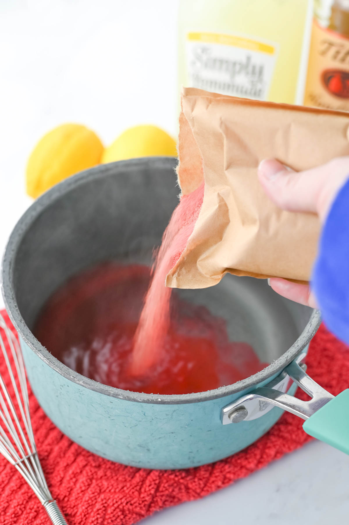 A person pouring jello powder into a pan.