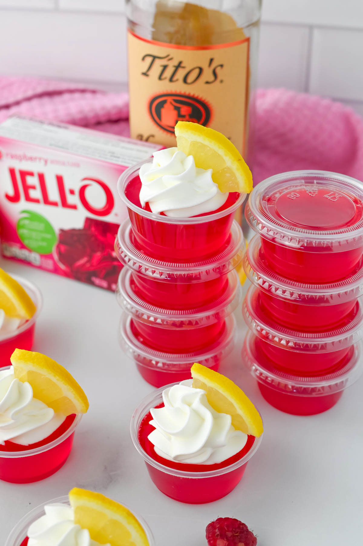 A tray of jello shots with lemon slices and a bottle of tito's.