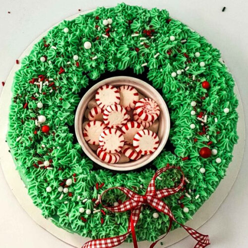 A festive Christmas wreath cake adorned with green frosting and candy canes.