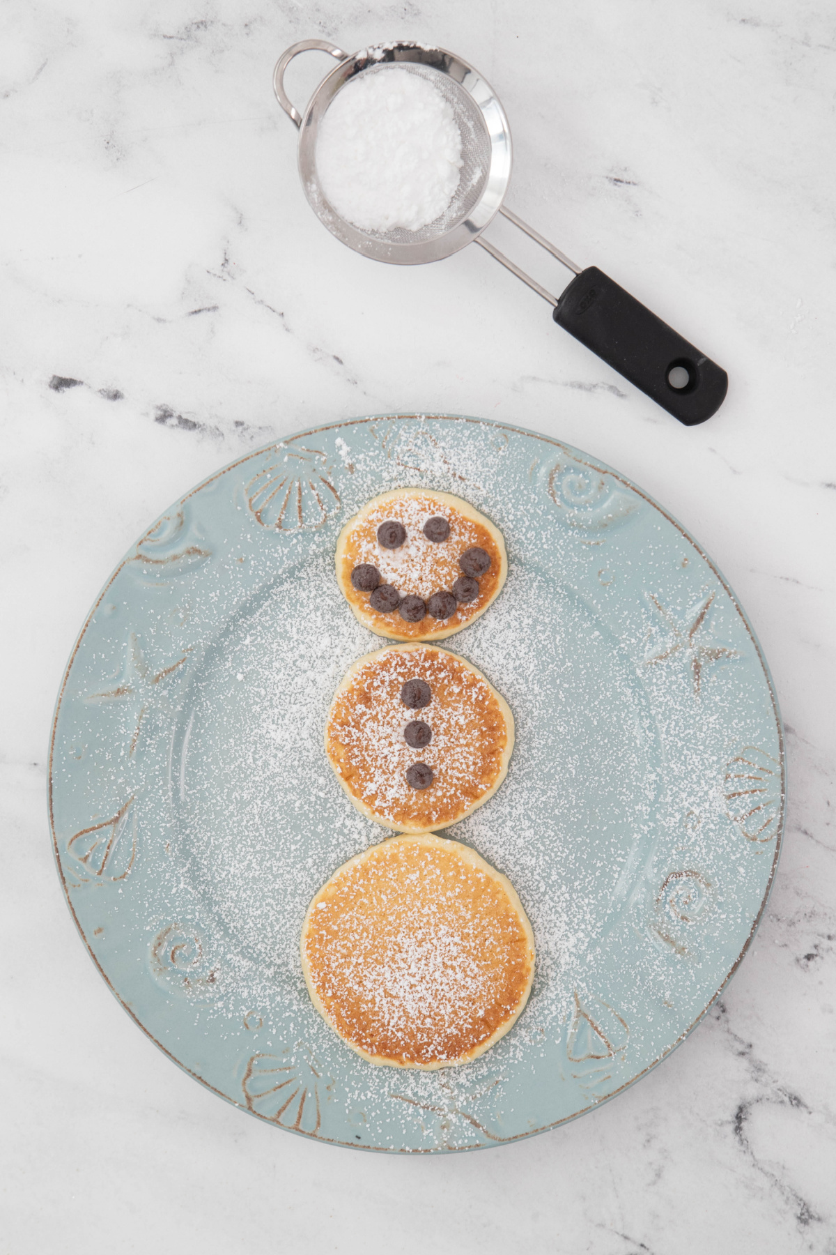 Pancakes shaped like a snowman on a plate.