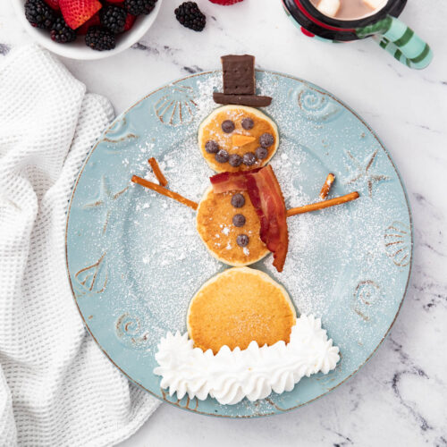 A plate of pancakes with a snowman pancake on it.