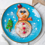 A plate of snowman pancakes with a blue background