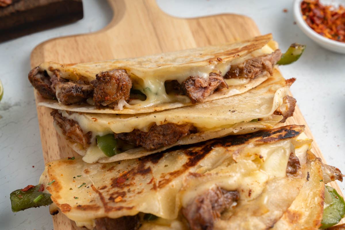 A stack of quesadillas on a wooden cutting board.