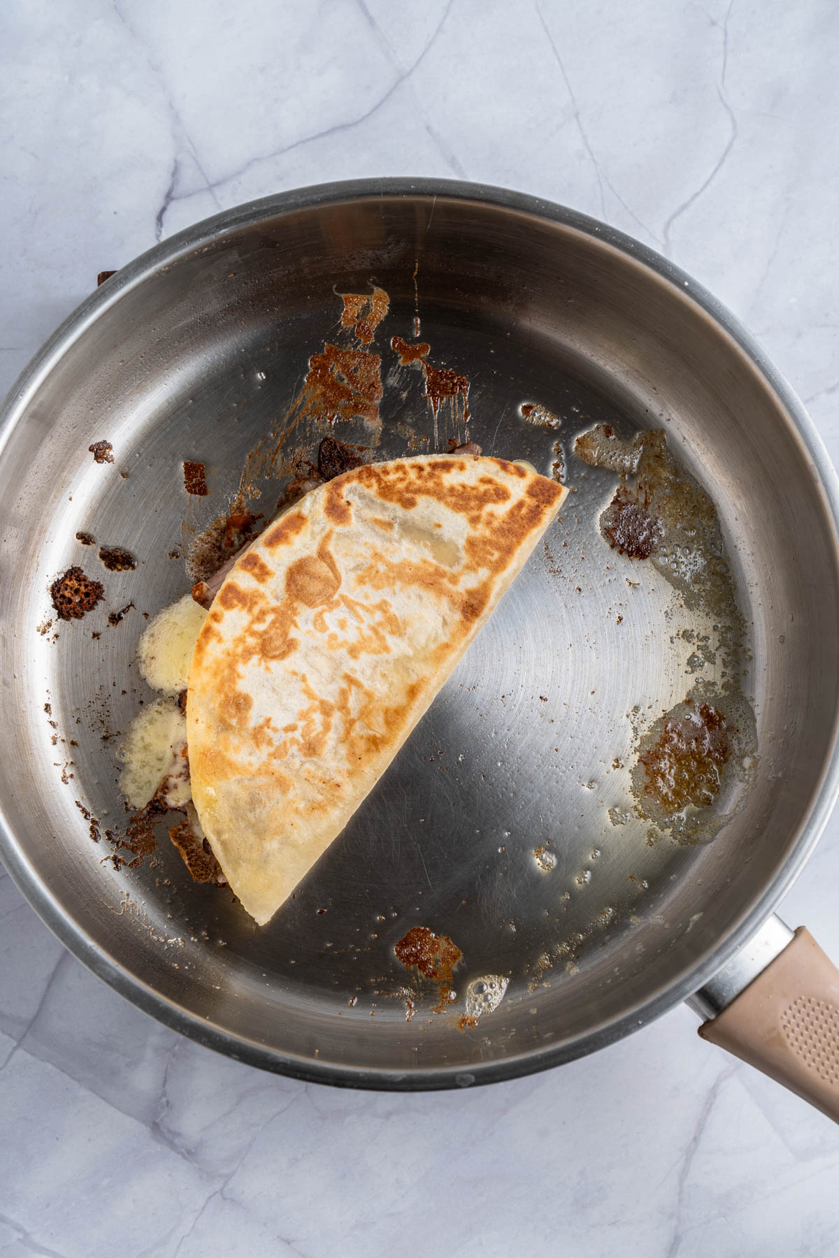 A quesadilla halved in a frying pan.