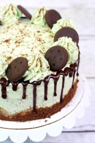 A green and white cake with cookies on top.