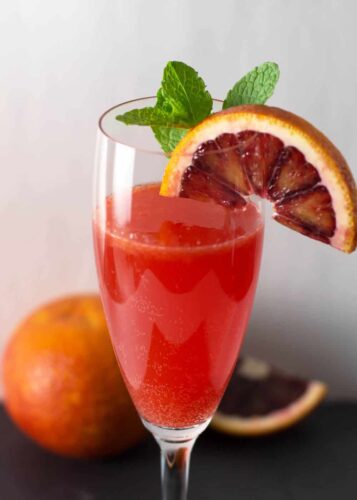 A blood orange cocktail with a slice of orange and mint.