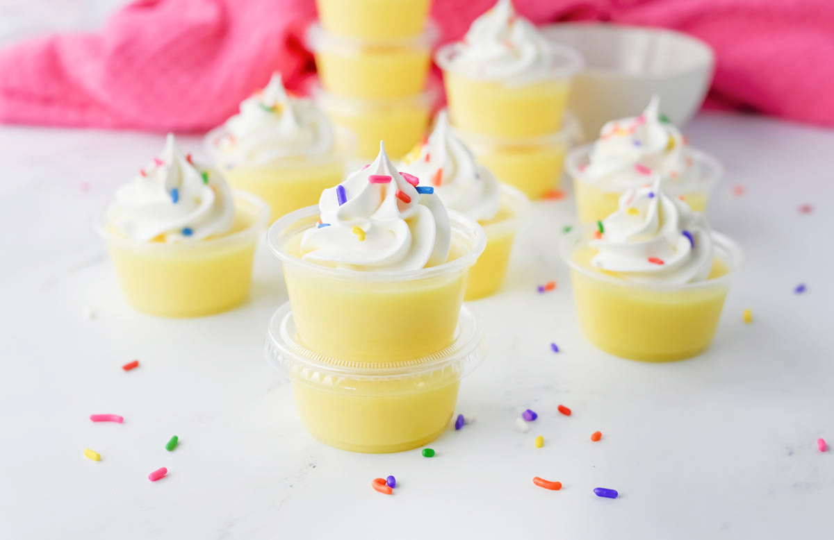 Birthday cake pudding shots topped with whipped cream and sprinkles.