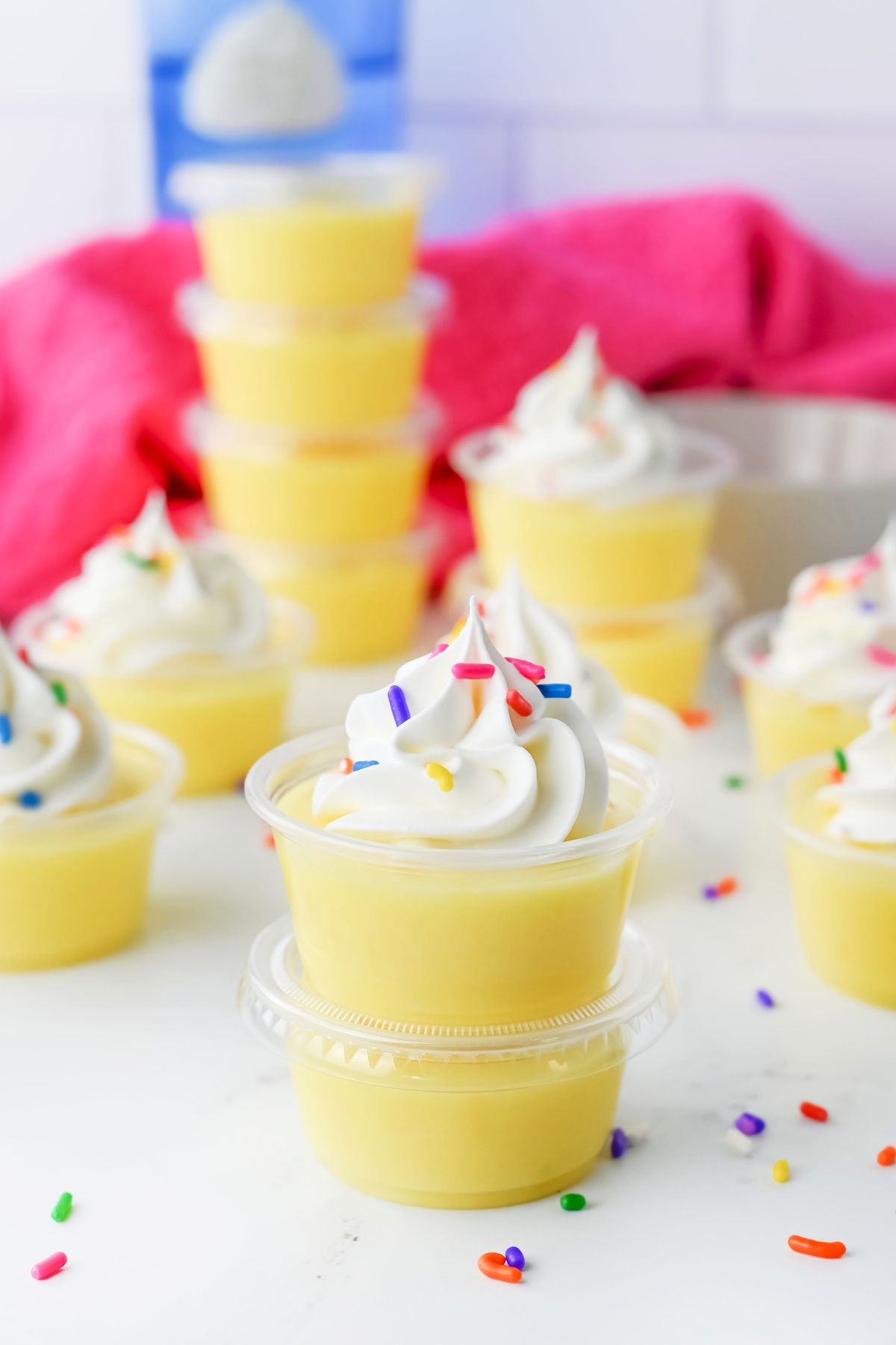Lemon pudding cups topped with whipped cream and sprinkles.