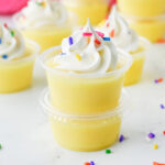 Pudding shots topped with whipped cream and sprinkles.