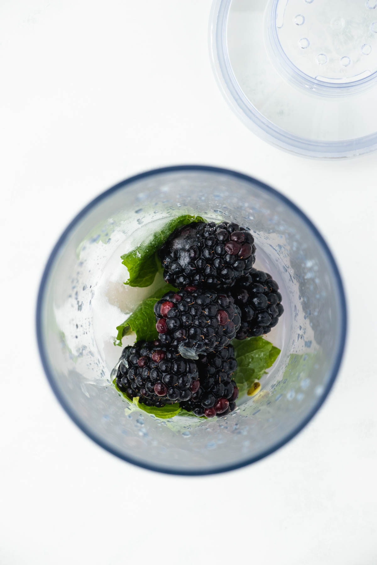 A glass with blackberries and mint leaves.