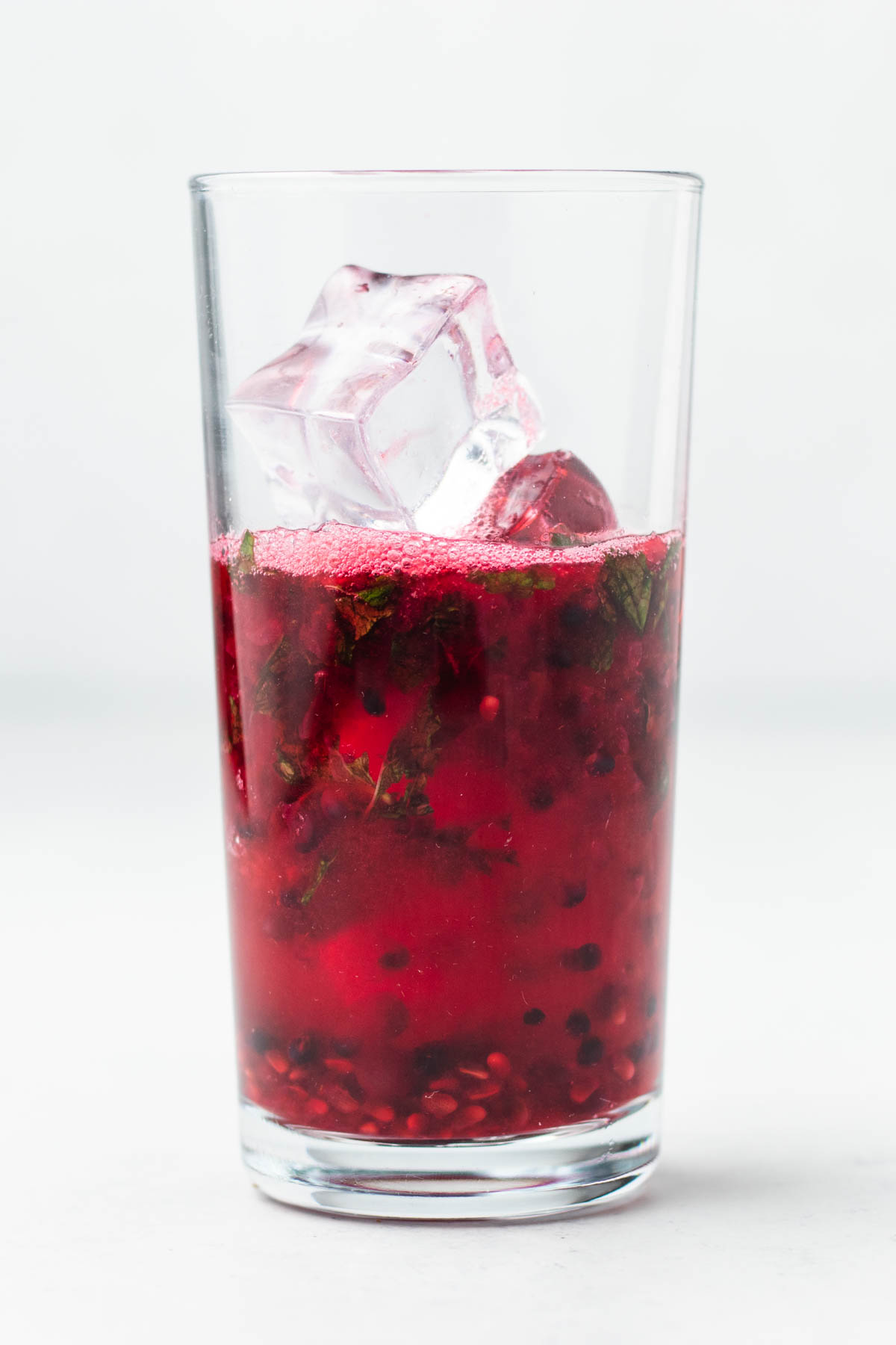 A glass with a blackberry drink and ice cubes.
