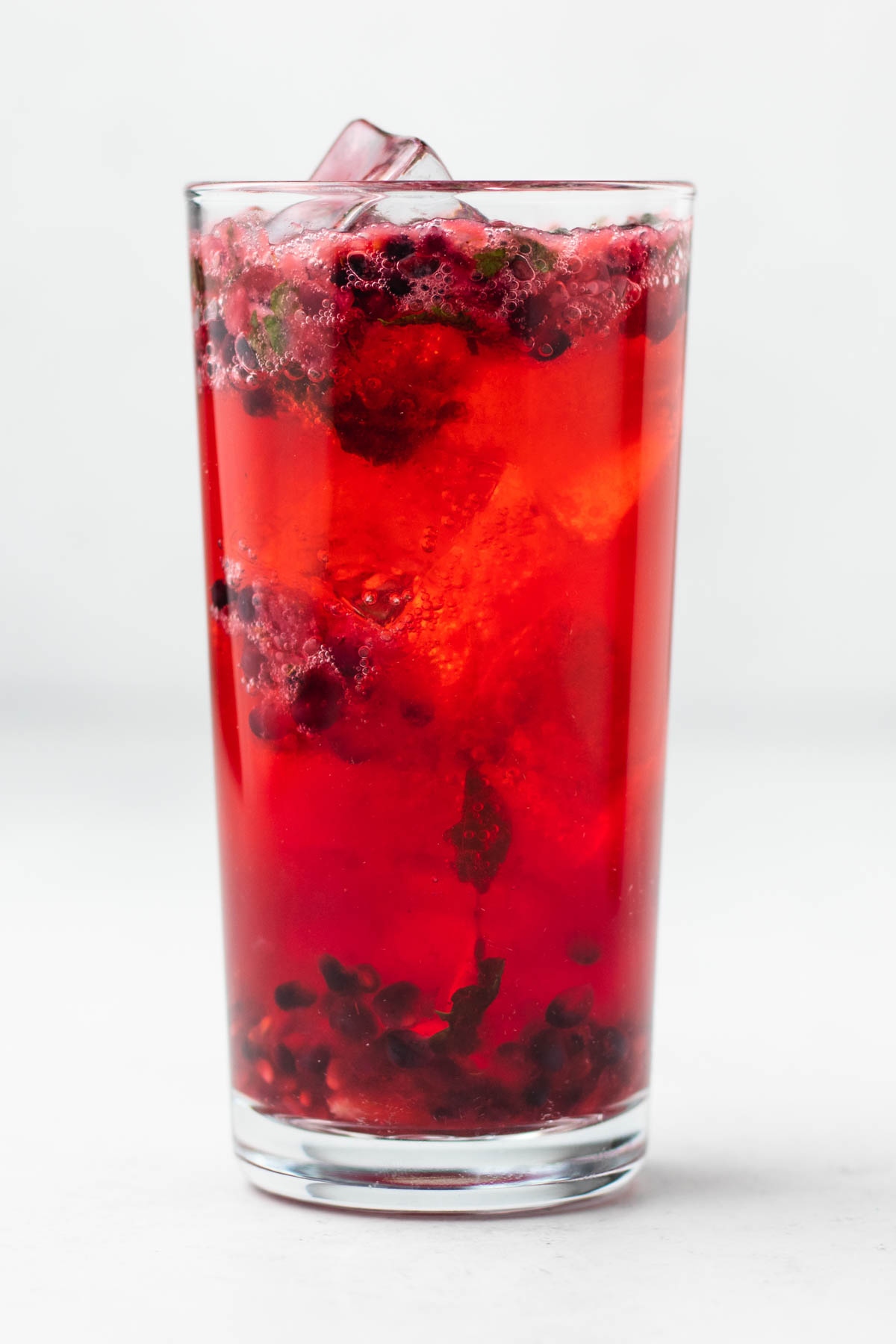 A glass of blackberry mojito with ice and mint.