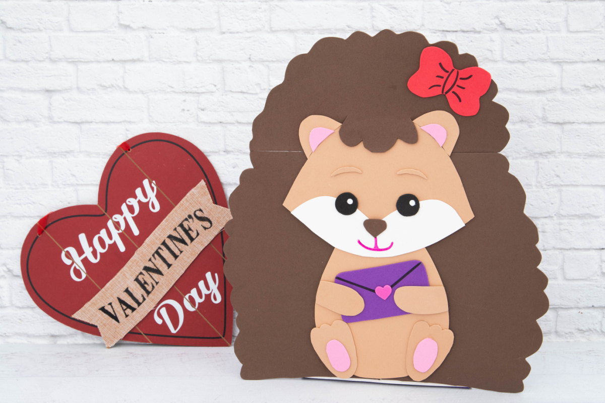 A foam cut out of a hedgehog holding a letter.
