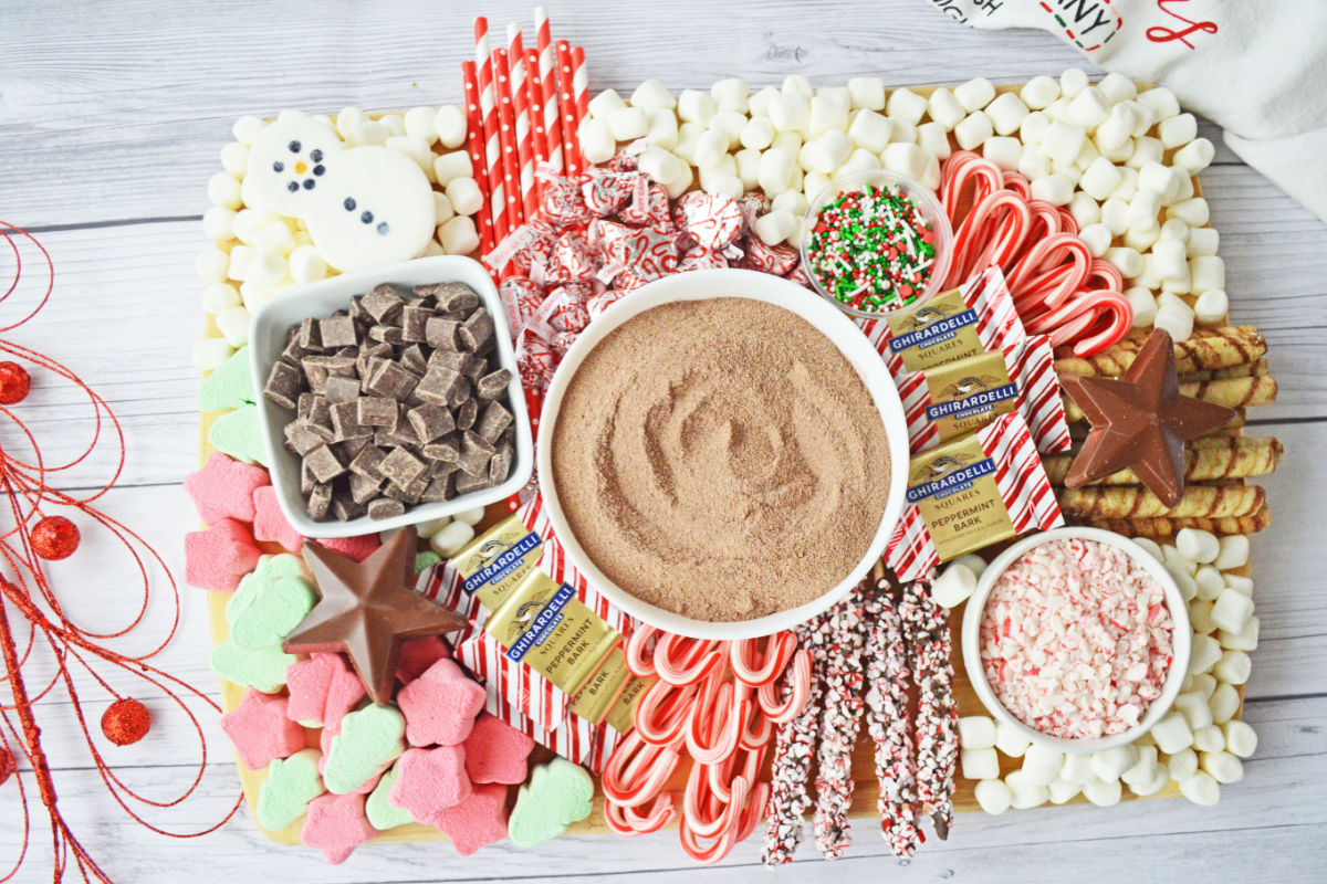 A festive charcuterie board for Christmas featuring a variety of desserts, including chocolate dip and candy canes.