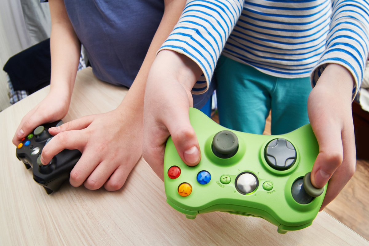 Two children playing video game controllers on a table.