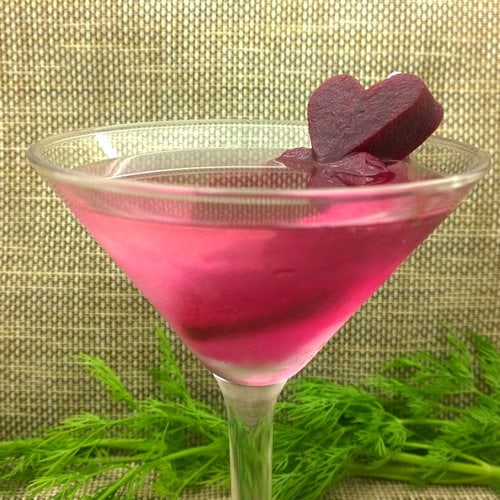 A martini with beets and a heart shaped garnish.