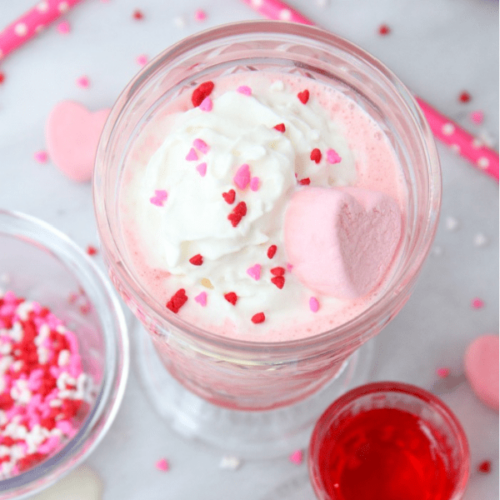 A valentine's day milkshake with marshmallows and whipped cream.