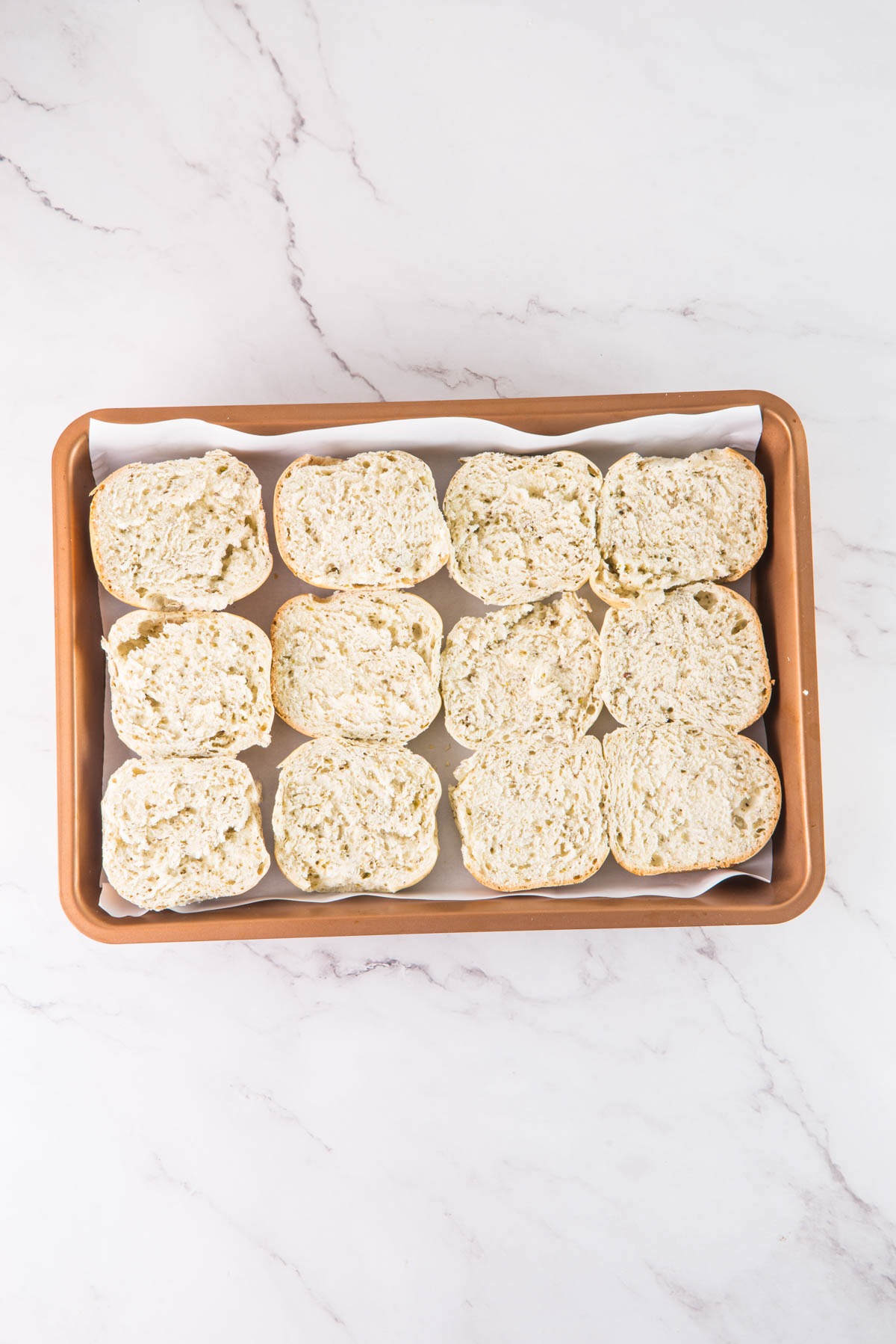 Bread rolls in a brown tray on a marble countertop.