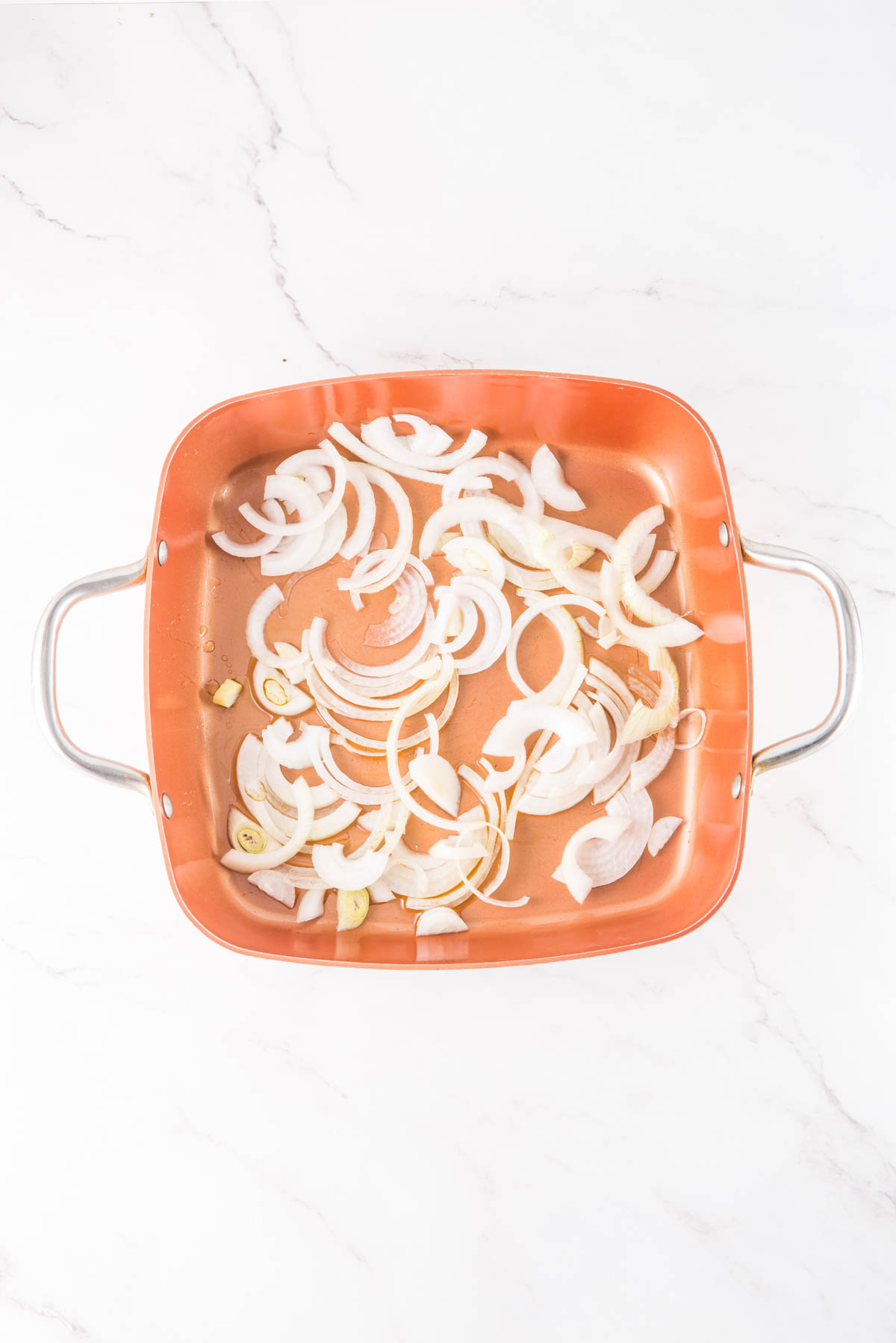 An orange baking dish filled with onions.