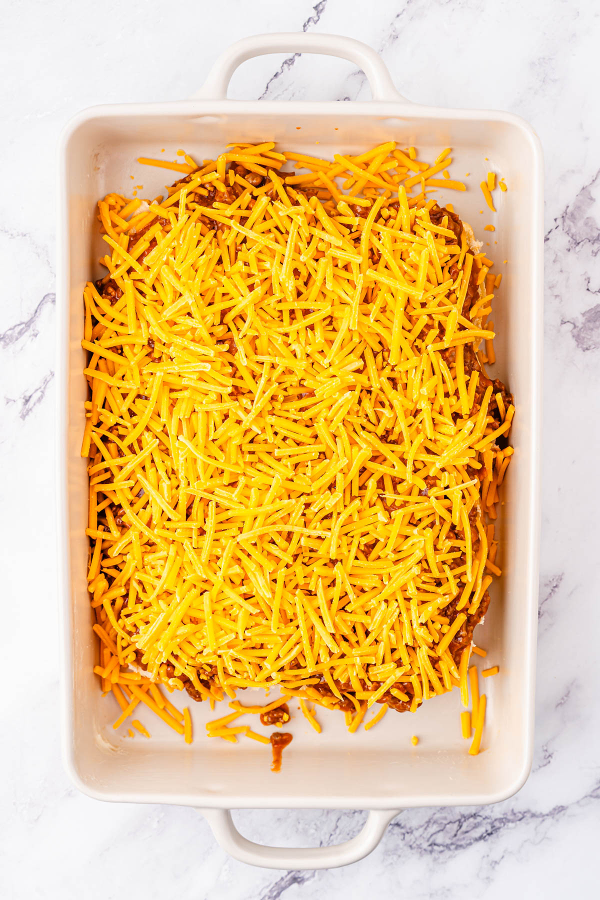 A casserole dish with cheese and meat on buns