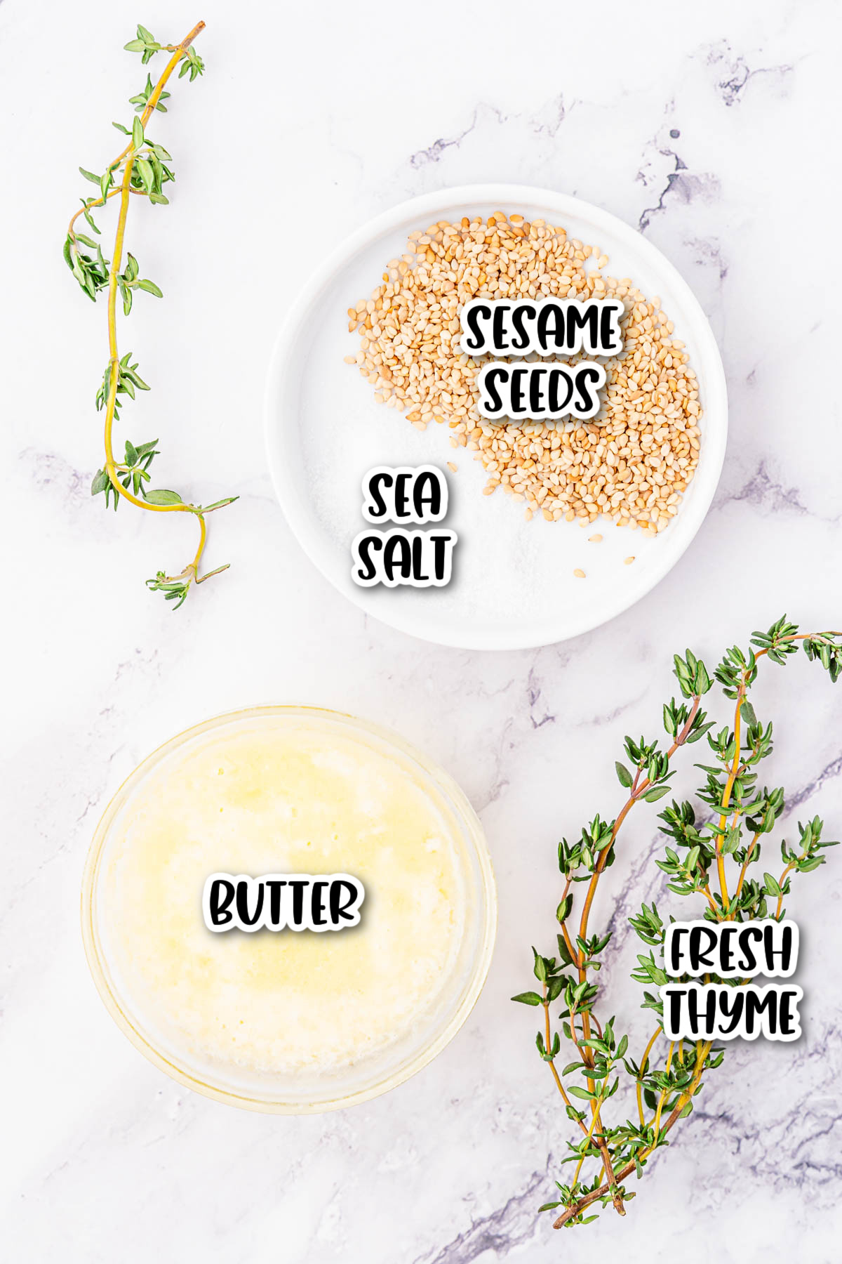 Thyme, sea salt, and other ingredients on a marble countertop.