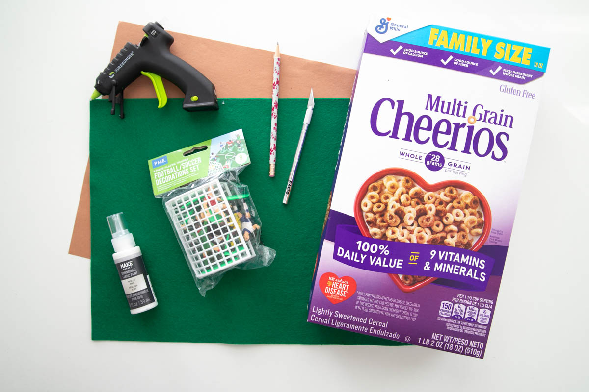An empty box of cereal, glue, scissors and glue sticks on a table.