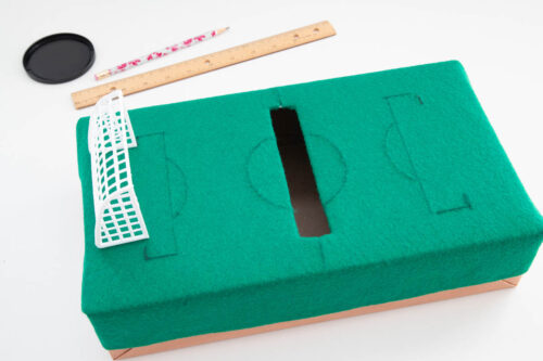 A green box with scissors and a ruler next to it.