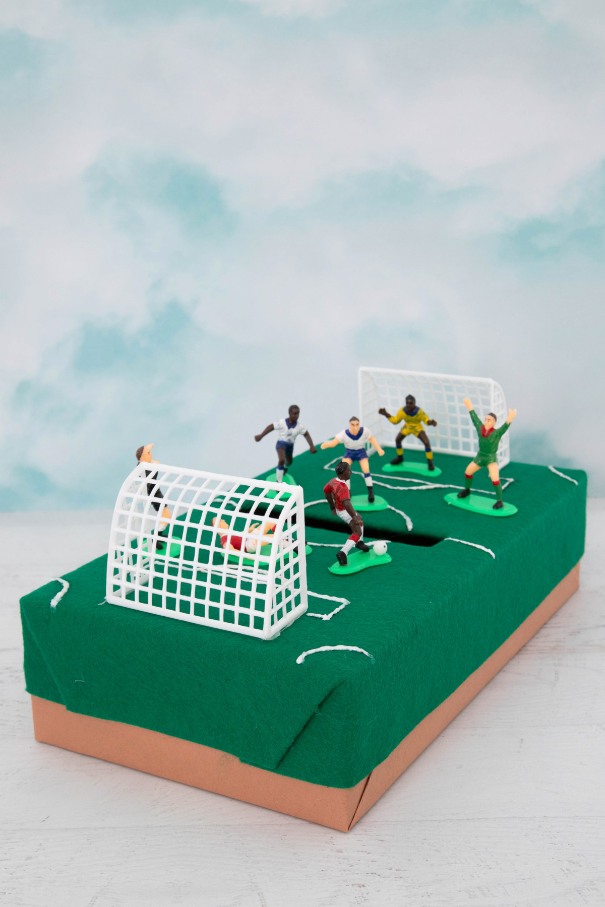 A box with soccer figurines on a green field.