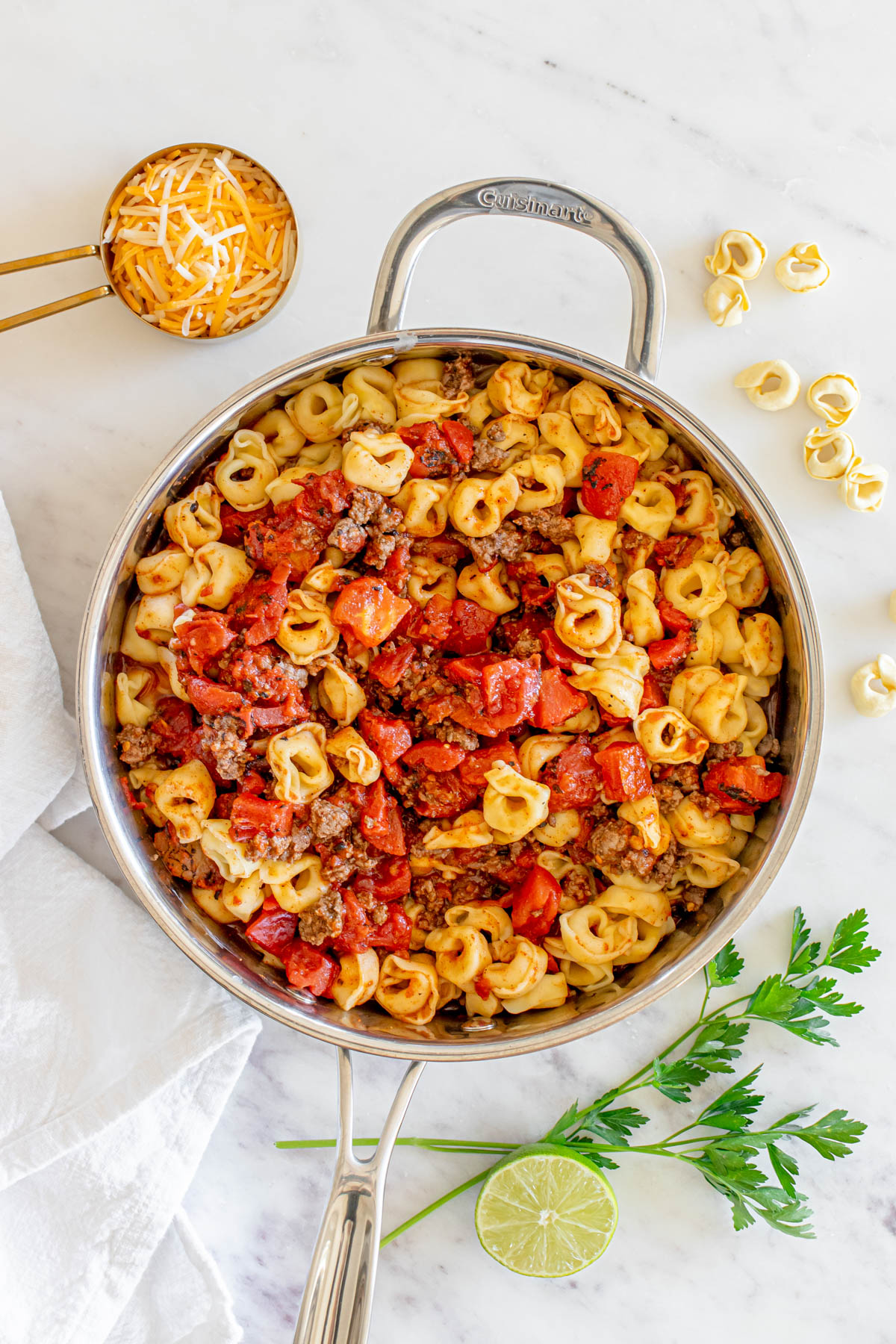 A skillet full of pasta with meat and tomatoes.