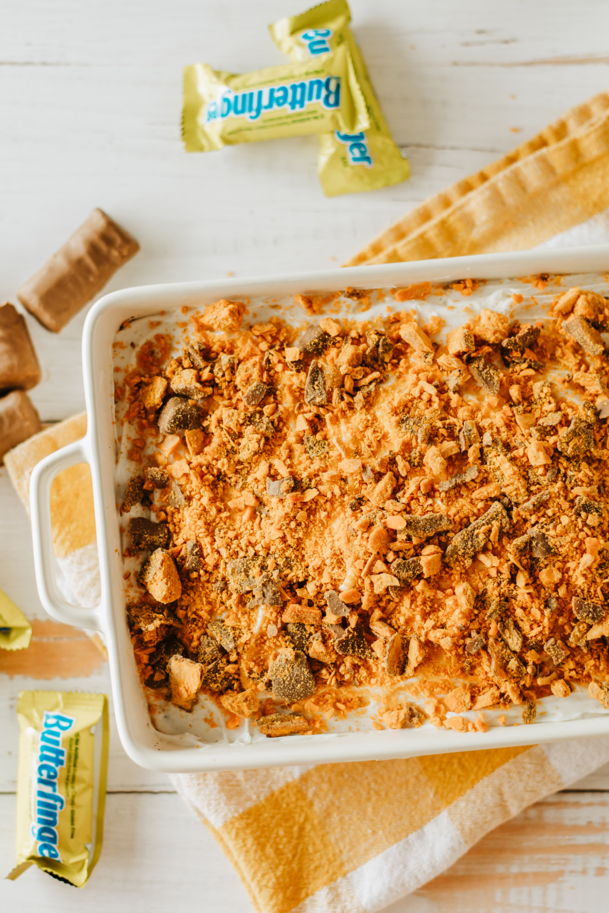 A baking dish with a cake topped with Butterfinger cookies