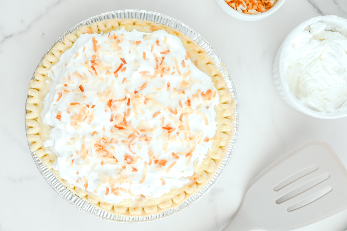 Coconut cream pie with whipped cream and coconut shavings.