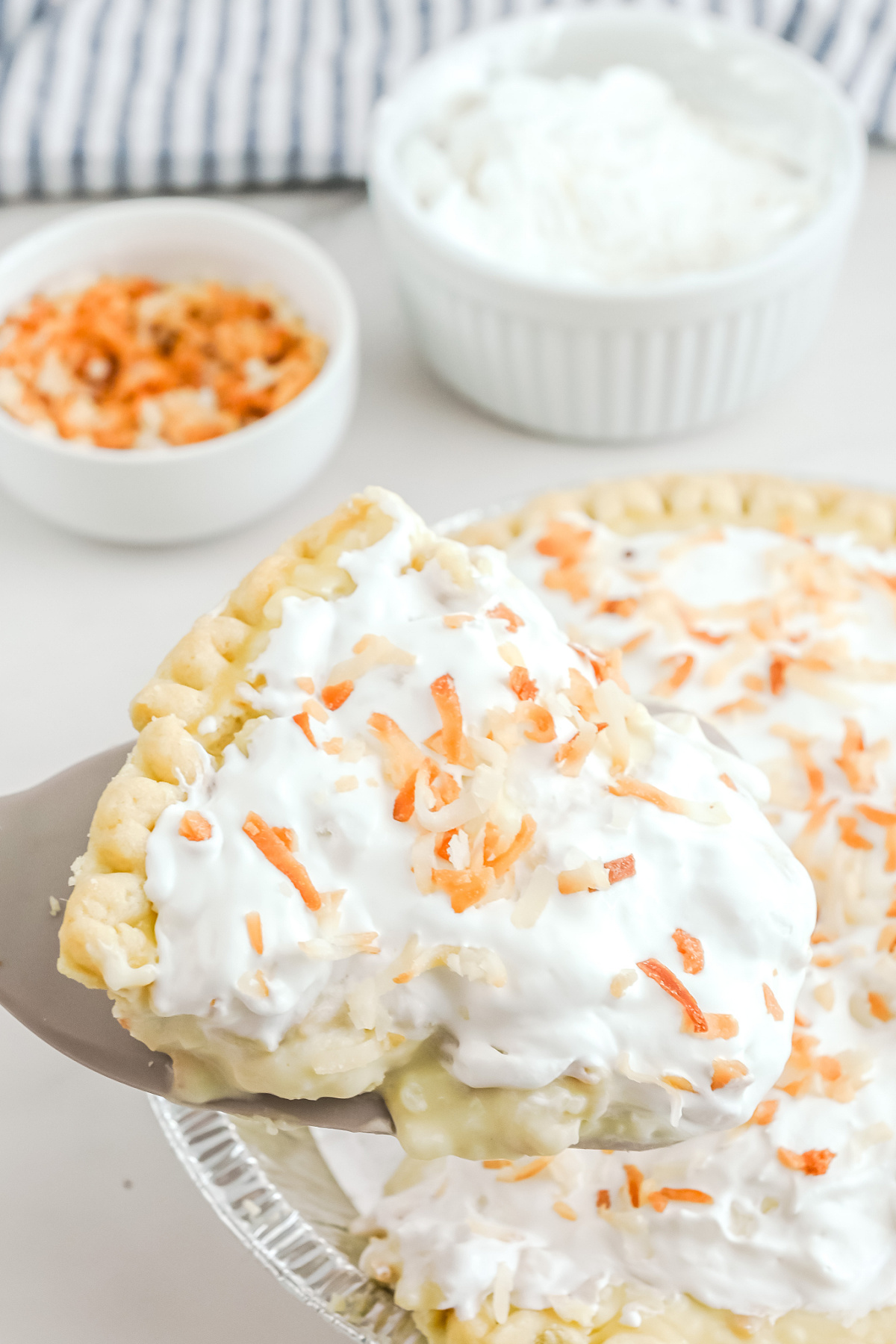 A slice of coconut cream pie with whipped cream and coconut.