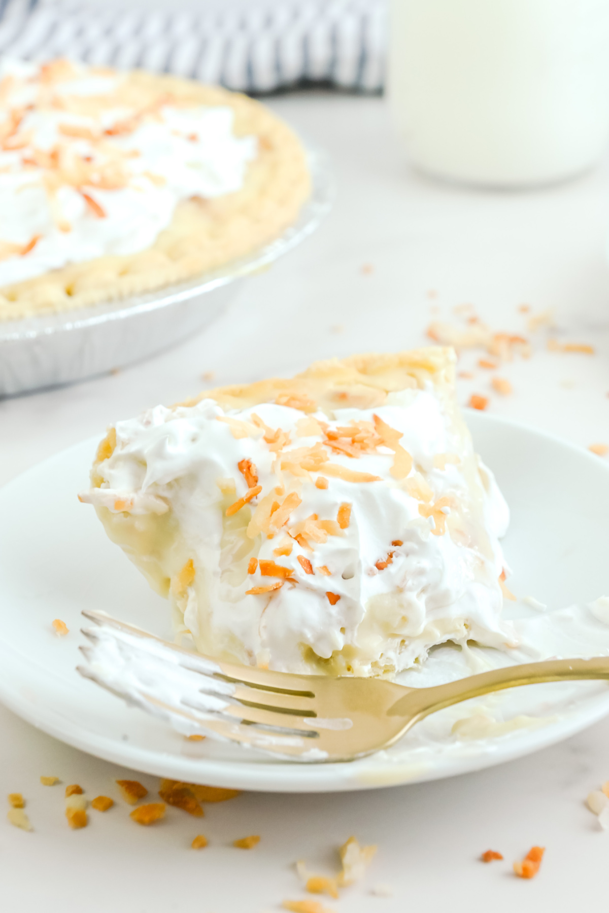 A slice of coconut cream pie with a bite taken out of it