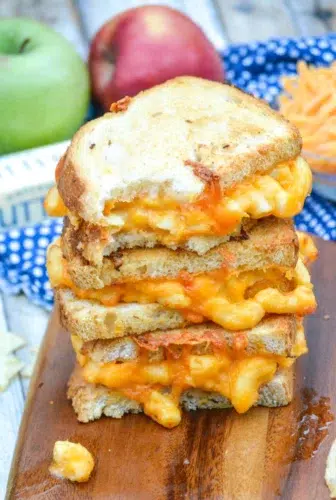 A stack of cheese and macaroni grilled cheese on a cutting board.