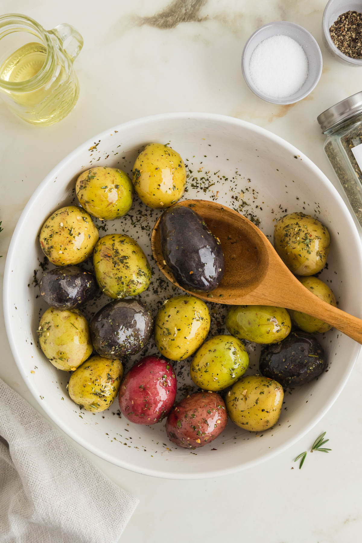 Roasted potatoes with seasoning in a white bowl.