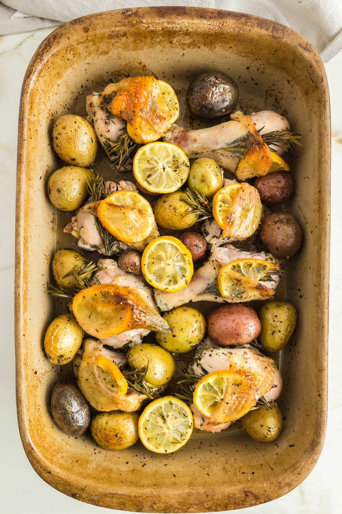 Roasted chicken with potatoes and lemons in a baking dish.