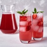 Two glasses of a strawberry mocktail with ice and mint.