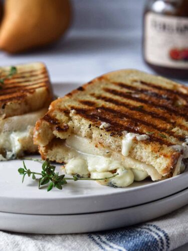 A grilled cheese sandwich with pears on a plate.