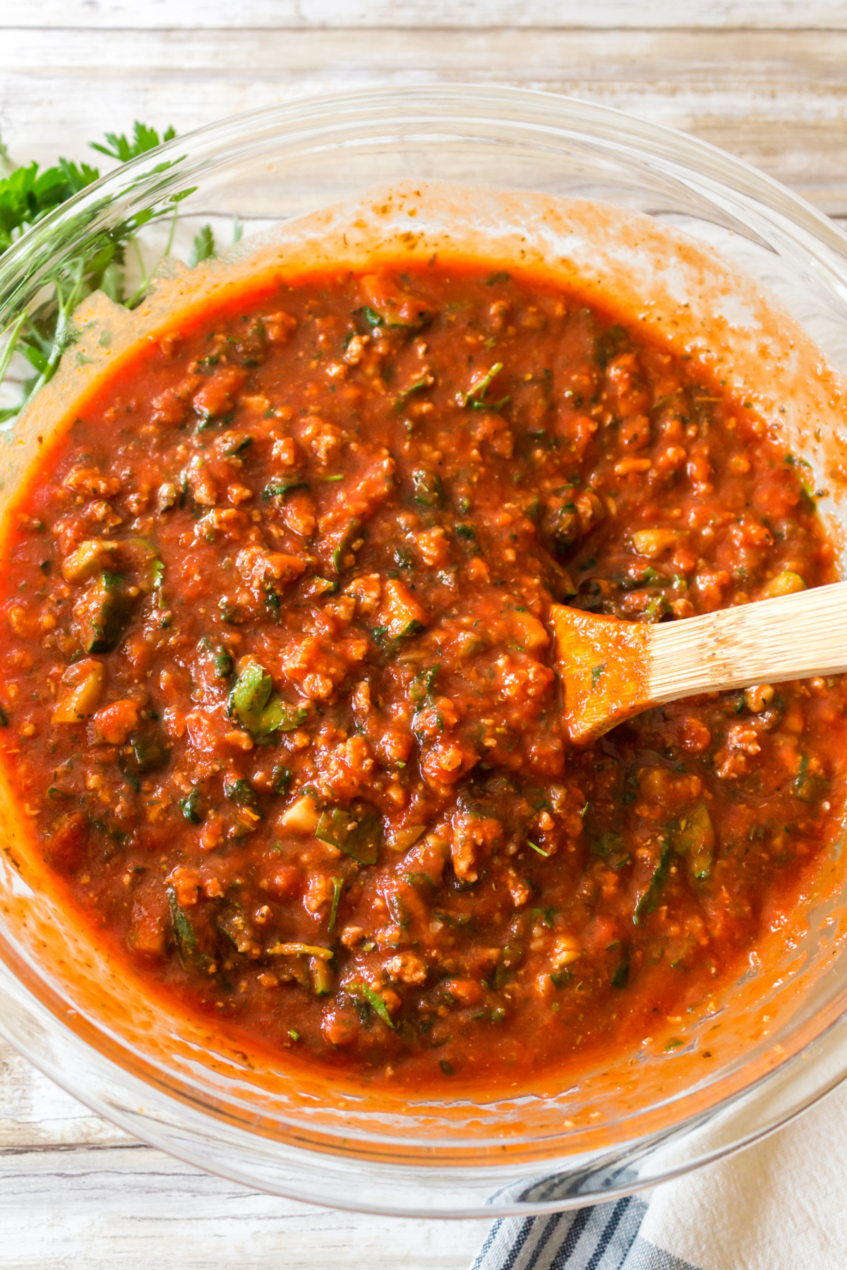 A bowl of homemade marinara sauce with a wooden spoon.